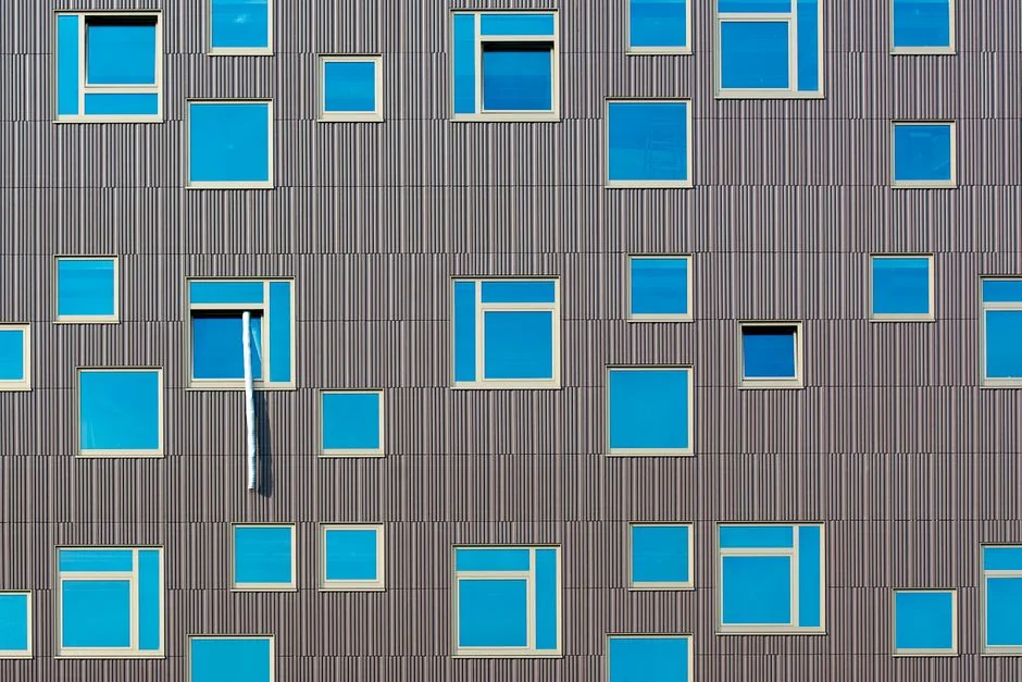 A worker cleaning skyscraper windows with a harness in an urban setting.